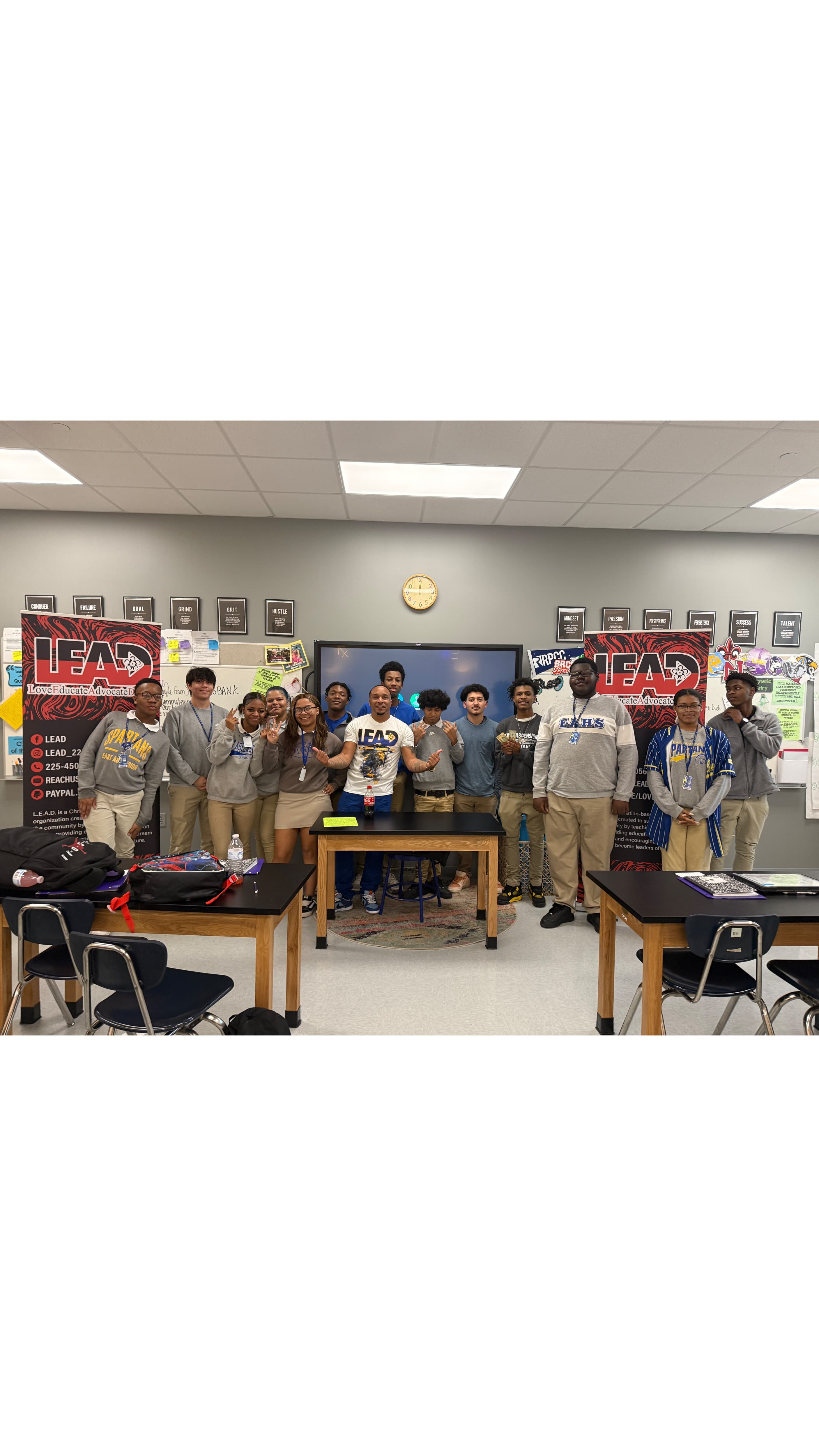 Mentor with group of high school students in classroom setting with LEAD program banners